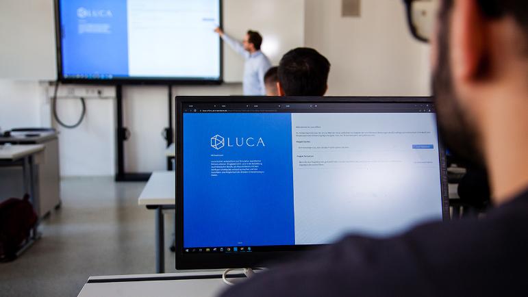 Schüler schaut auf einen Monitor, auf dem die Software LUCA Office Simulation abgebildet ist