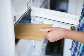 Hand nimmt Brief aus Briefkasten